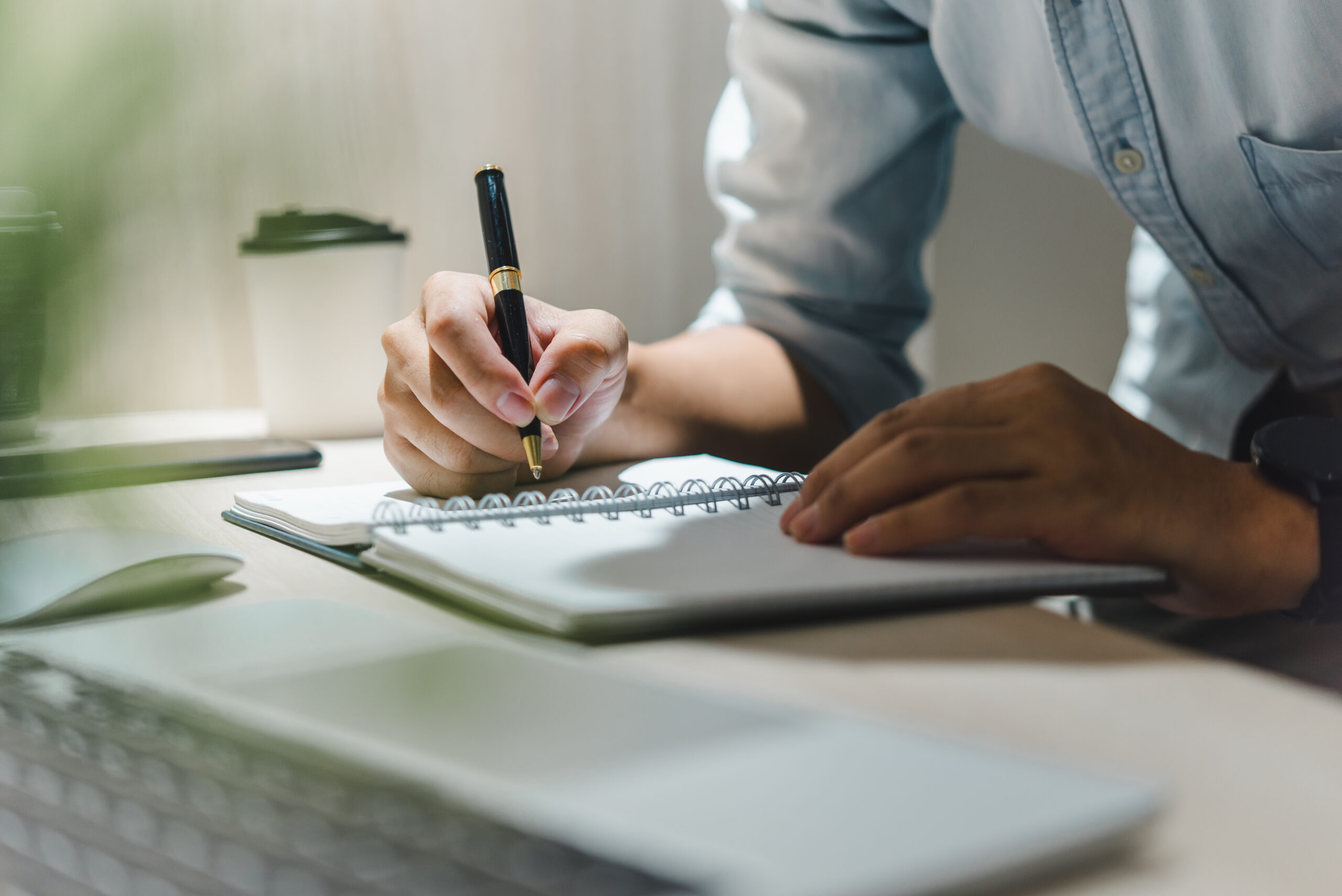 man hands with pen writing on notebook in the office.learning, education and work.writes goals, plans, make to do and wish list on desk.